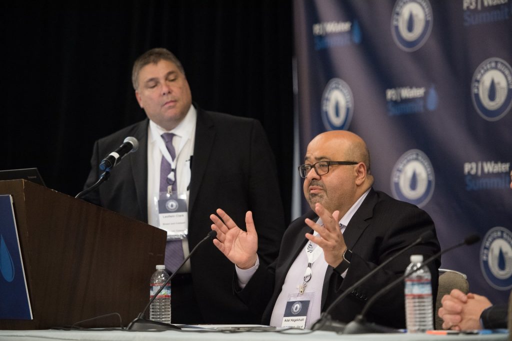 man standing behind lectern looking at seated man answering a question